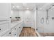 Bright bathroom featuring double sinks, white cabinetry, and a glass-enclosed shower with wood-look flooring at 3235 E Easter Pl, Centennial, CO 80122
