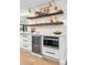 Kitchen wet bar with a wine refrigerator, microwave and beautiful open shelving with accent lighting at 3235 E Easter Pl, Centennial, CO 80122