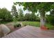 A large grassy backyard with a deck, brick trim, mulch, and large trees at 7140 S Uinta St, Centennial, CO 80112