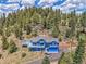 Aerial view showcases this blue home with a deck, nestled among towering trees, with a driveway at 33633 Elk Run, Evergreen, CO 80439