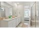 Bright bathroom featuring double sinks, a marble countertop, and a glass-enclosed shower with a built-in bench at 8052 Mount Kataka St, Littleton, CO 80125