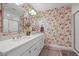 Bathroom with a dual vanity, floral wallpaper, and framed mirror over a tile floor at 6705 S Catawba Way, Aurora, CO 80016