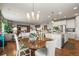 Open-concept dining area with hardwood floors, elegant chandelier, and a view of the adjacent kitchen and living room at 6705 S Catawba Way, Aurora, CO 80016