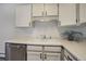Close up of kitchen sink with stainless steel dishwasher, white cabinets, gray vinyl floors at 3164 S Wheeling Way # 101, Aurora, CO 80014