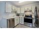 Kitchen with stainless steel dishwasher and range, gray vinyl floors and white cabinets at 3164 S Wheeling Way # 101, Aurora, CO 80014