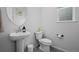 Cozy powder room featuring a pedestal sink, round mirror, and tile floors at 4792 Coltin Trl, Castle Rock, CO 80104