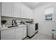 Laundry room with modern washer and dryer, white cabinets, and sink with modern fixtures at 4792 Coltin Trl, Castle Rock, CO 80104