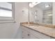 Bright bathroom featuring a granite countertop, sink, and a mirror reflecting the shower with a glass door at 3292 S Wabash Ct, Denver, CO 80231