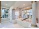 Bright bathroom features a soaking tub with marble surround, columns, and natural light from the window at 22911 E Euclid Cir, Aurora, CO 80016