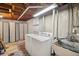Basement laundry room with exposed beam ceiling, washer, dryer, and wash sink at 2792 S Stuart St, Denver, CO 80236