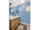Stylish bathroom features a modern vanity, a round mirror, and eye-catching blue walls at 4647 W Dakota Ave, Denver, CO 80219