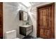 Stylish bathroom with modern vanity, decorative lighting, and dark wood door, complemented by a mosaic floor at 1030 S Adams St, Denver, CO 80209