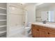 A bathroom featuring white tile, wood cabinets and a shower and bathtub combo at 6391 S Malaya St, Centennial, CO 80016