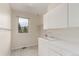 Bright laundry room features white cabinets, tile countertop with sink and a window for natural light at 6391 S Malaya St, Centennial, CO 80016
