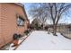 Side yard of the house with snow, trees, and a fence at 7900 E Dartmouth Ave # 76, Denver, CO 80231