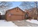 Two-car garage and brick front exterior in a snowy winter setting at 7900 E Dartmouth Ave # 76, Denver, CO 80231