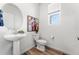 Stylish powder room with a modern pedestal sink, wood-look floors, and natural light at 1043 High Point Trl, Elizabeth, CO 80107