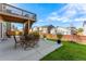 Outdoor patio with a full table and chairs underneath a raised wooden deck overlooks a lush lawn and fence at 1043 High Point Trl, Elizabeth, CO 80107