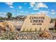 Coyote Creek Golf Course community entrance featuring stone signage and landscaping with flowers near parking area at 2184 Alyssa St, Fort Lupton, CO 80621