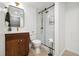 This bathroom offers a modern design with white walls, wooden vanity, brass fixtures, and a glass shower at 1702 W 66Th Ave, Denver, CO 80221