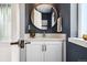 Stylish powder room with a round mirror, quartz countertops, and shaker cabinets at 1702 W 66Th Ave, Denver, CO 80221