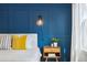 Close-up of bedroom showing paneled blue accent wall, side table, and window at 1702 W 66Th Ave, Denver, CO 80221