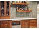This wet bar features custom walnut cabinetry, floating shelves, a white countertop, and a wine fridge at 1702 W 66Th Ave, Denver, CO 80221