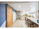 Open basement features a bar with stools, light wood floors, and a rustic sliding barn door at 10462 Hoyt St, Westminster, CO 80021