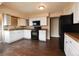 Functional kitchen with white cabinetry, black appliances, and wood-look flooring, ready for your personal touch at 5185 Alcott St, Denver, CO 80221