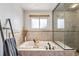 Bright bathroom featuring a soaking tub, shower with glass enclosure, and tile surround at 7106 S Kendall Blvd, Littleton, CO 80128