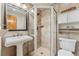 Updated bathroom with a glass-enclosed shower, pedestal sink, and modern fixtures at 7106 S Kendall Blvd, Littleton, CO 80128