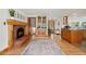 Open-concept living room with a brick fireplace, wooden floors, and seamless transitions to the kitchen and entryway for easy living at 7106 S Kendall Blvd, Littleton, CO 80128