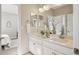 Modern bathroom featuring dual sinks with white cabinets, quartz countertops, and elegant decor at 17829 W 95Th Pl, Arvada, CO 80007