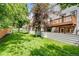 View of a grassy backyard, enclosed by a fence, with a balcony and trees at 6382 W Byers Pl, Lakewood, CO 80226