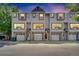 Exterior view of a row of townhomes, each with a garage and multiple windows on a tree lined street at 6382 W Byers Pl, Lakewood, CO 80226