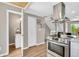 Spacious kitchen with stainless steel appliances, a modern hood vent, and an open view of the stairs at 6382 W Byers Pl, Lakewood, CO 80226