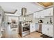 Open concept kitchen featuring stainless steel appliances, a modern hood vent and an open view of the living area at 6382 W Byers Pl, Lakewood, CO 80226