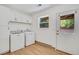 Bright laundry room features white cabinets, a window and an exterior door to backyard at 6382 W Byers Pl, Lakewood, CO 80226