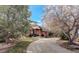 Inviting brick home with a circular driveway and mature trees against a blue sky at 1036 Lexington Ave, Westminster, CO 80023