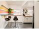 Compact kitchen featuring a breakfast bar, modern stools, and a vibrant accent wall design at 2774 W Irvington Pl, Denver, CO 80219