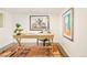 Home office area with a rustic wooden desk, bonsai tree, and colorful rugs against a white wall backdrop at 2774 W Irvington Pl, Denver, CO 80219