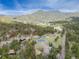 Aerial view of neighborhood with mature trees, tennis courts, and scenic mountain views in the background at 4198 Timbervale Dr, Evergreen, CO 80439