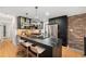 Kitchen featuring an island with black countertop, pendant lighting, stainless steel appliances, and brick accent wall at 1111 Monroe St, Denver, CO 80206