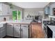 Open concept kitchen features gray cabinets, wood accents, stainless appliances, and views to the dining and living areas at 8764 W 95Th Ave, Broomfield, CO 80021