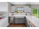 Charming kitchen featuring white cabinets, a farmhouse sink, stainless appliances, and views to the backyard at 8764 W 95Th Ave, Broomfield, CO 80021