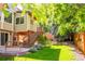 Manicured backyard featuring a patio, stairs to a deck, lush greenery, and a privacy fence at 10565 Kalahari Ct, Lone Tree, CO 80124