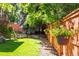 A lush backyard oasis featuring a manicured lawn, privacy fence with hanging flower baskets, and mature trees at 10565 Kalahari Ct, Lone Tree, CO 80124