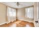 Bright bedroom featuring hardwood floors, a ceiling fan, and two windows with sheer curtains at 2840 S Heather Gardens Way # A, Aurora, CO 80014