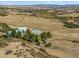 Aerial shot of a ranch house surrounded by dry fields and large trees at 4880 Tall Horse Trl, Sedalia, CO 80135