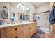 Well-lit bathroom featuring double sinks, wood cabinets, and tiled shower with glass door at 4880 Tall Horse Trl, Sedalia, CO 80135